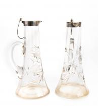 A pair of glass pitchers with silver lid